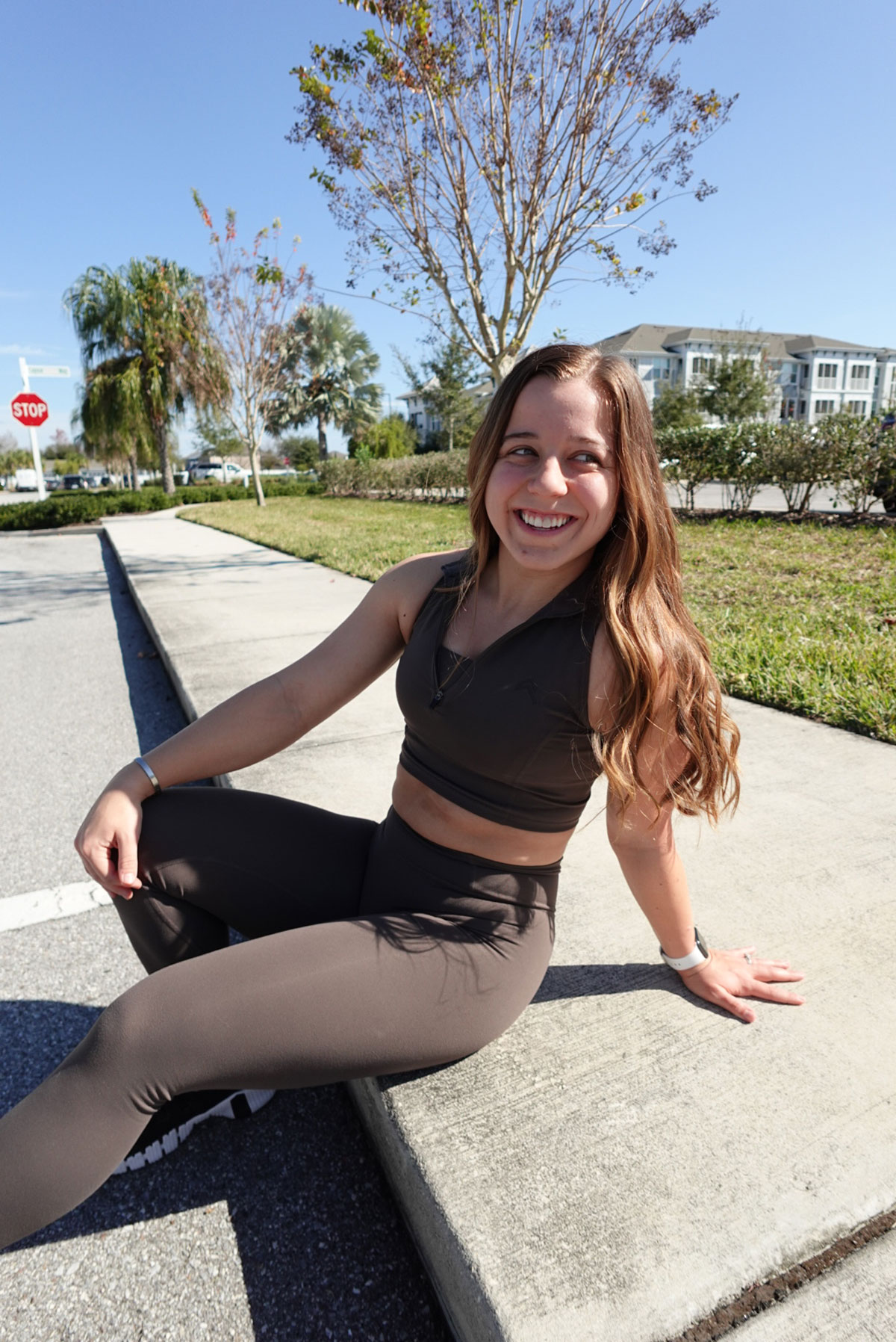 Maddie sitting on a sidewalk, smiling.